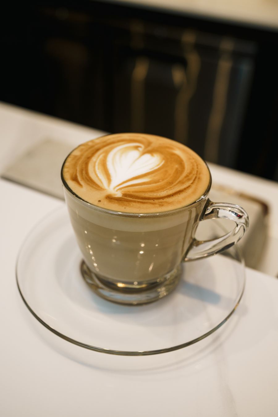 Cappuccino with a heart in the latte art on a glass saucer