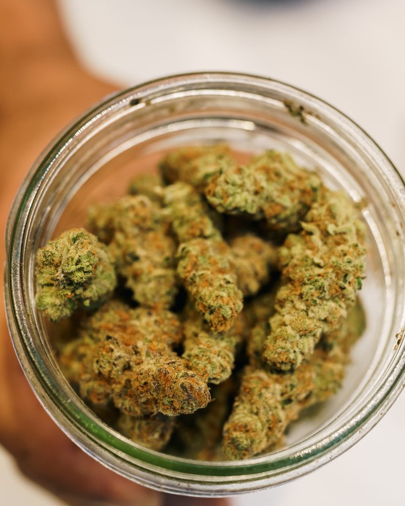 Glass-jar cured cannabis flower at the counter of Coffeeshop The Mantis, Ao Nang