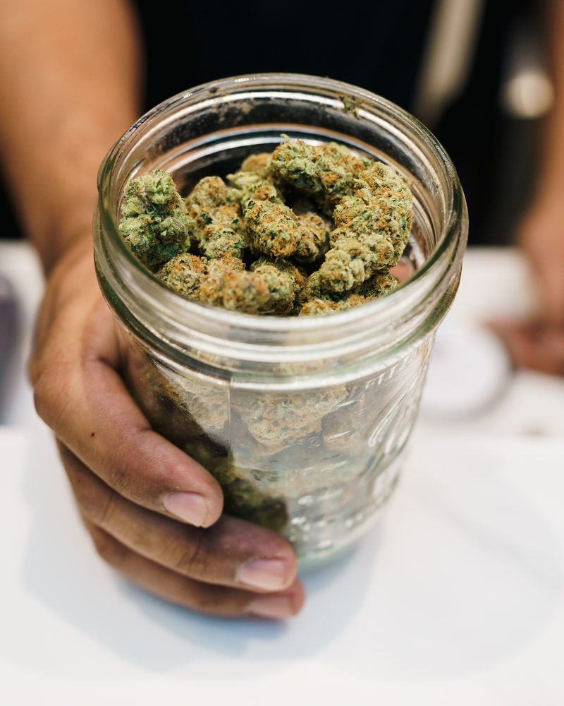 Glass-jar cured cannabis flower at the counter of Coffeeshop The Mantis, Ao Nang