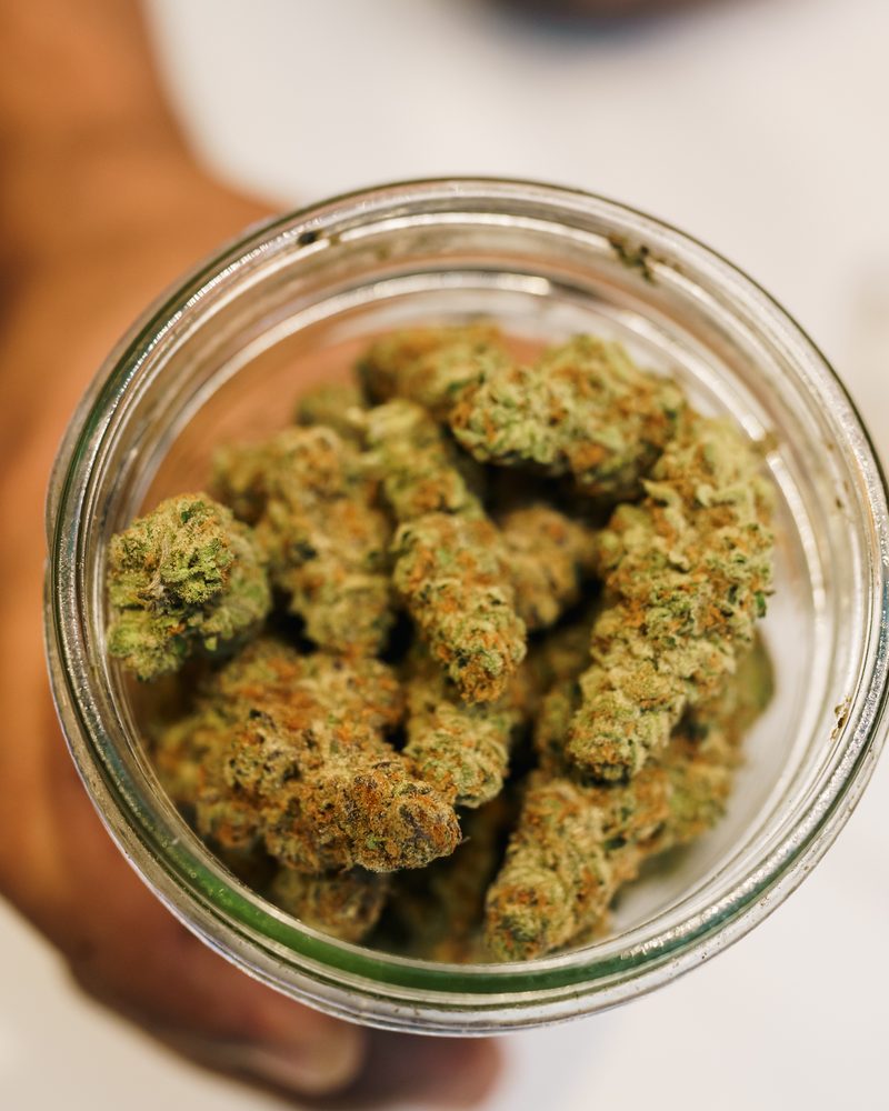 Glass-jar cured cannabis flower at the counter of Coffeeshop The Mantis, Ao Nang