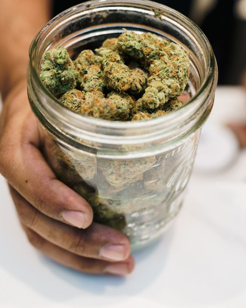 Glass-jar cured cannabis flower at the counter of Coffeeshop The Mantis, Ao Nang