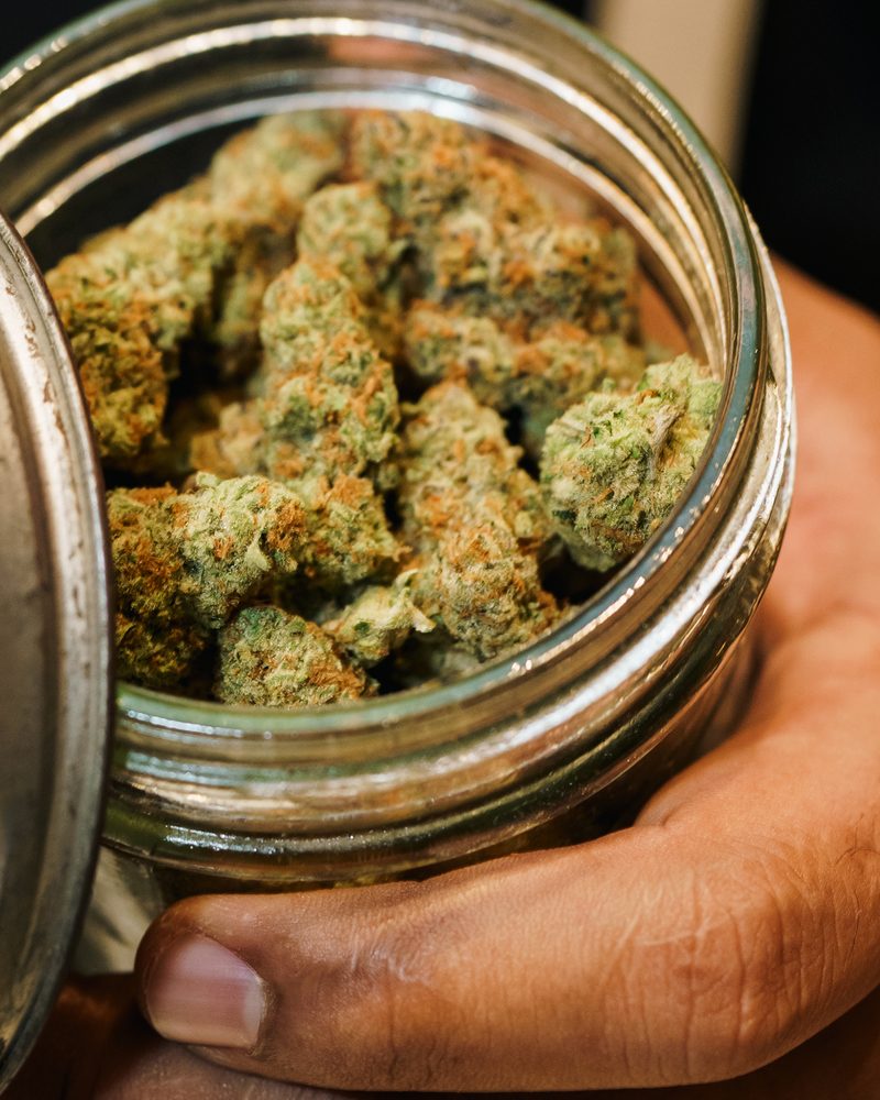 Glass-jar cured cannabis flower at the counter of Coffeeshop The Mantis, Ao Nang