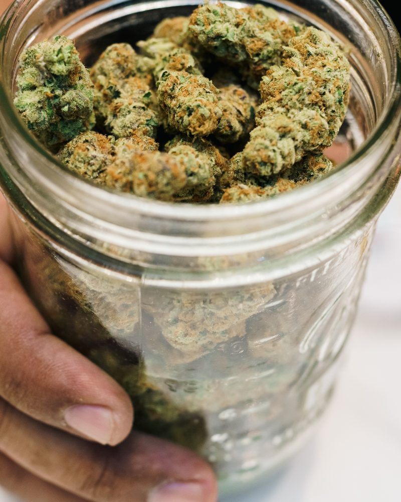 Glass-jar cured cannabis flower at the counter of Coffeeshop The Mantis, Ao Nang