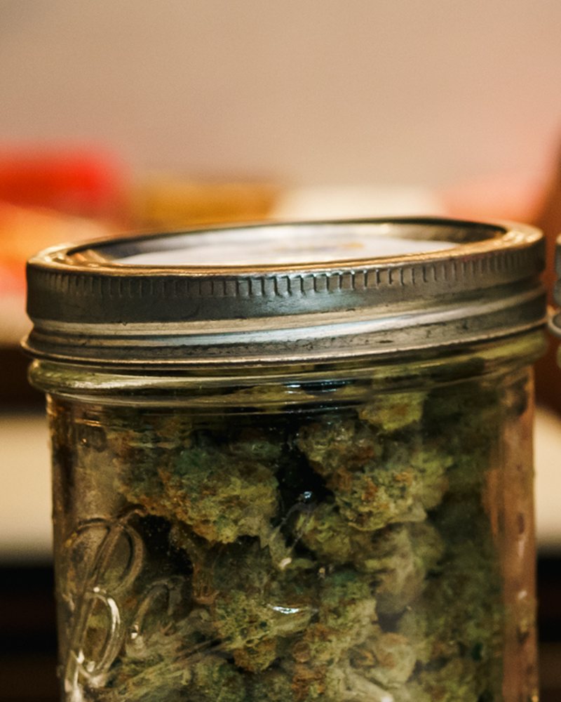 Glass-jar cured cannabis flower at the counter of Coffeeshop The Mantis, Ao Nang