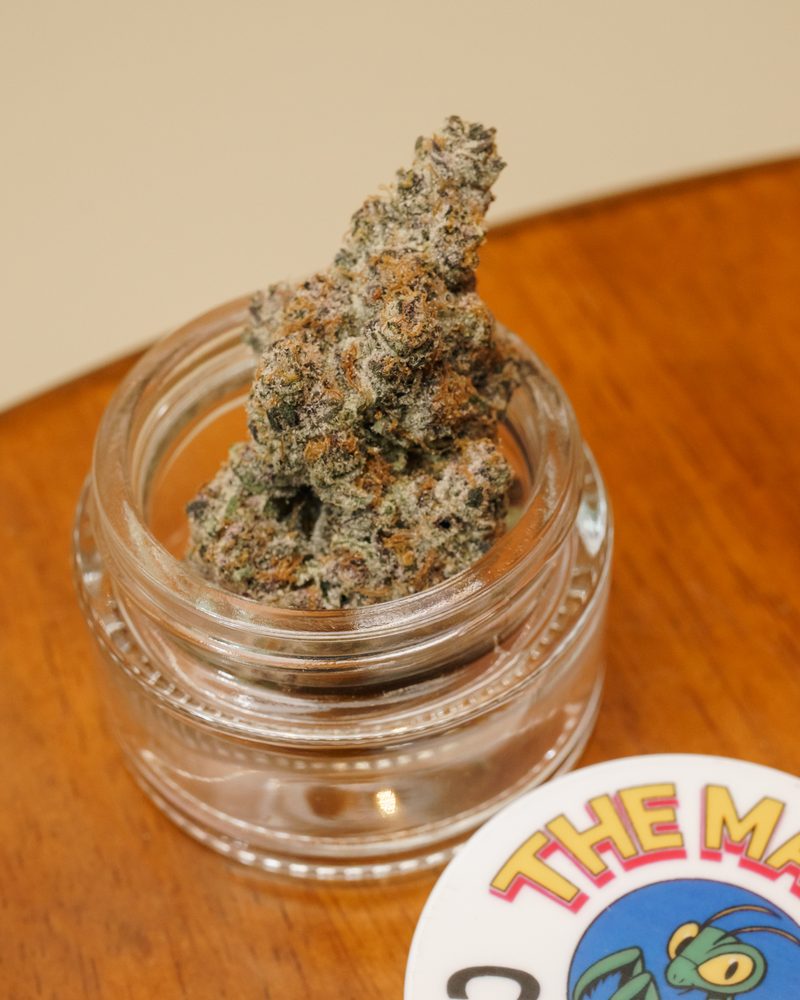 Glass-jar cured cannabis flower at the counter of Coffeeshop The Mantis, Ao Nang