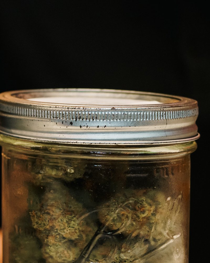 Glass-jar cured cannabis flower at the counter of Coffeeshop The Mantis, Ao Nang
