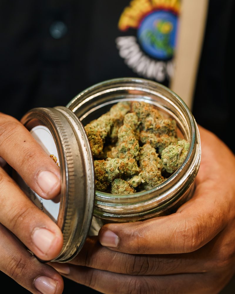 Glass-jar cured cannabis flower at the counter of Coffeeshop The Mantis, Ao Nang