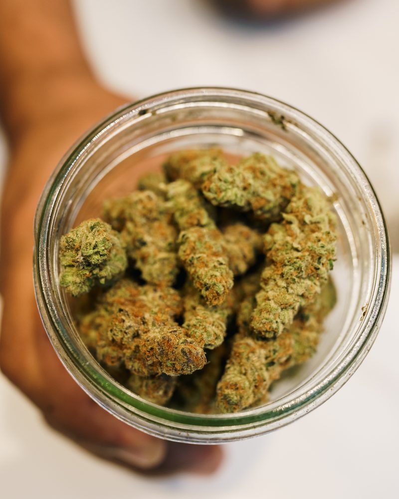 Glass-jar cured cannabis flower at the counter of Coffeeshop The Mantis, Ao Nang