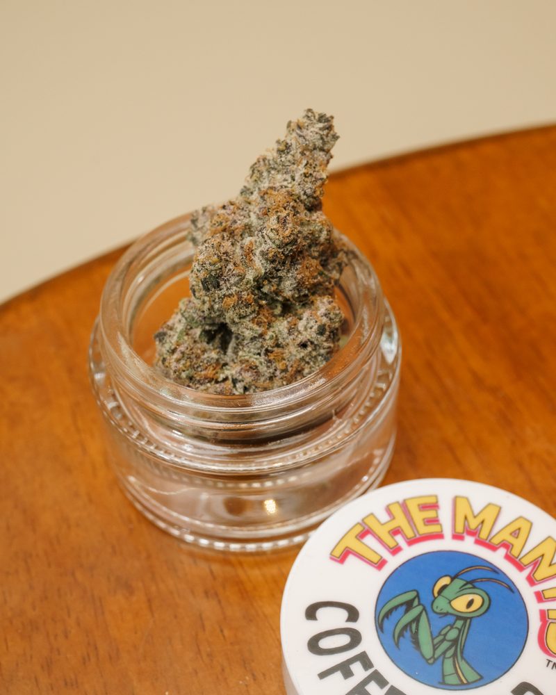Glass-jar cured cannabis flower at the counter of Coffeeshop The Mantis, Ao Nang
